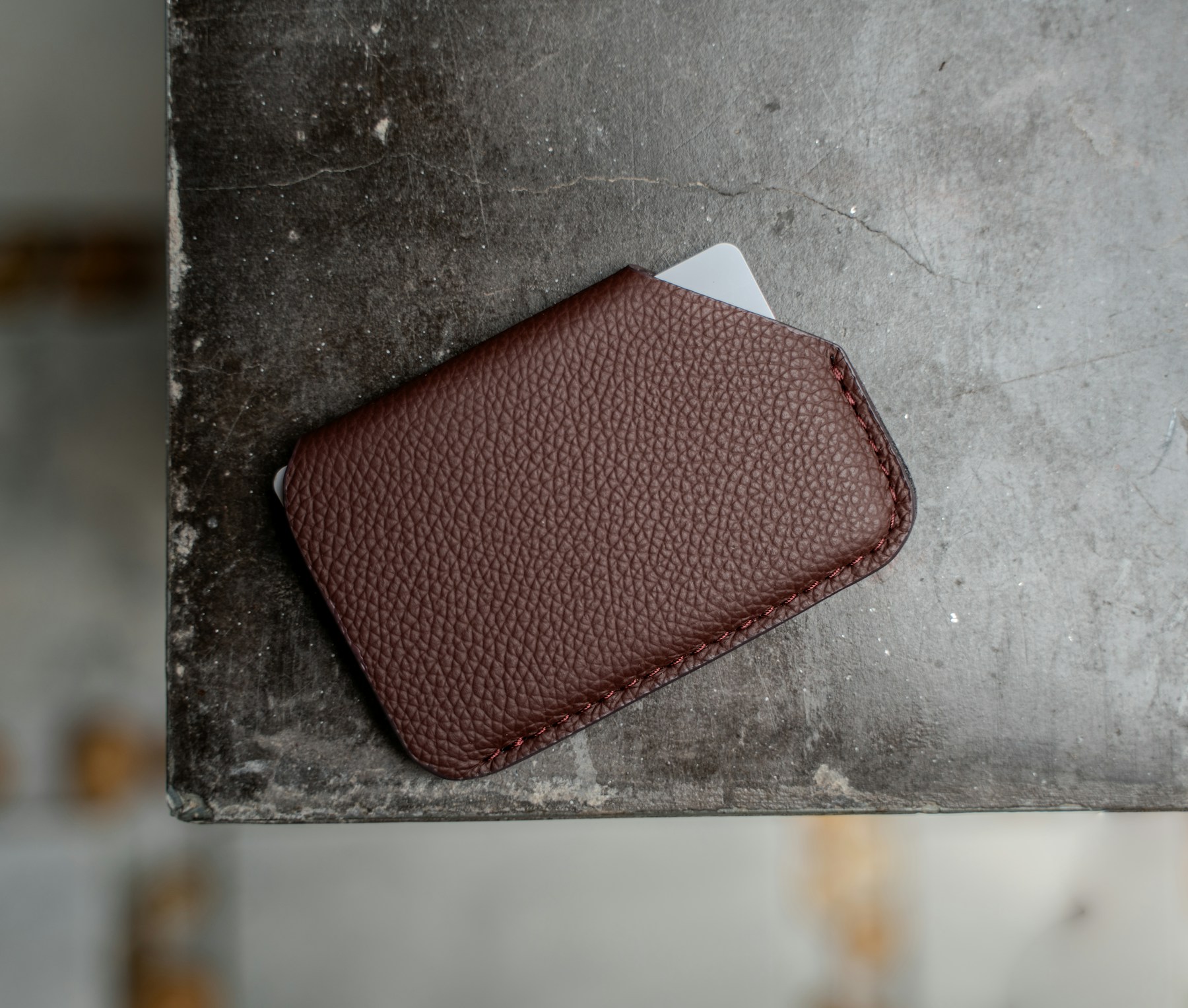 Brown full-grain leather card holder on an artisan work surface
